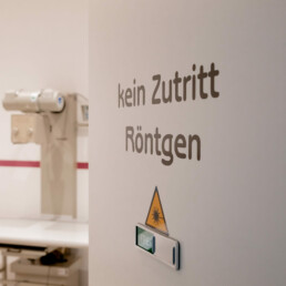 Auf dem Bild ist die geöffnete Tür des Röntgenraumes der Praxis abgebildet, was an der Aufschrift 